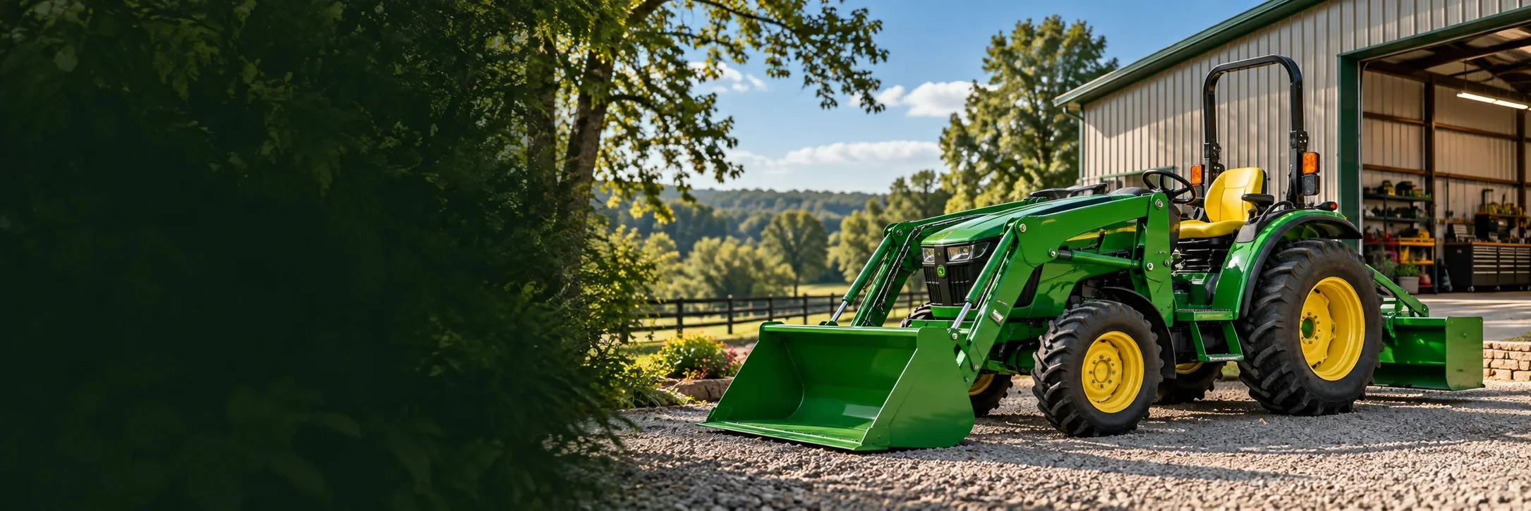 Compact tractor with a front loader parked beside a workshop